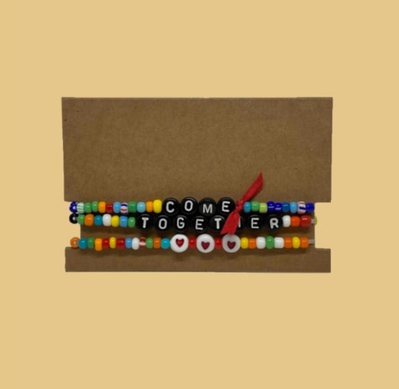 Conjunto de pulseiras coloridas com a frase "come together", de Roxanne Assoulin, para a inauguração do governo Joe Biden e Kamala Harris.