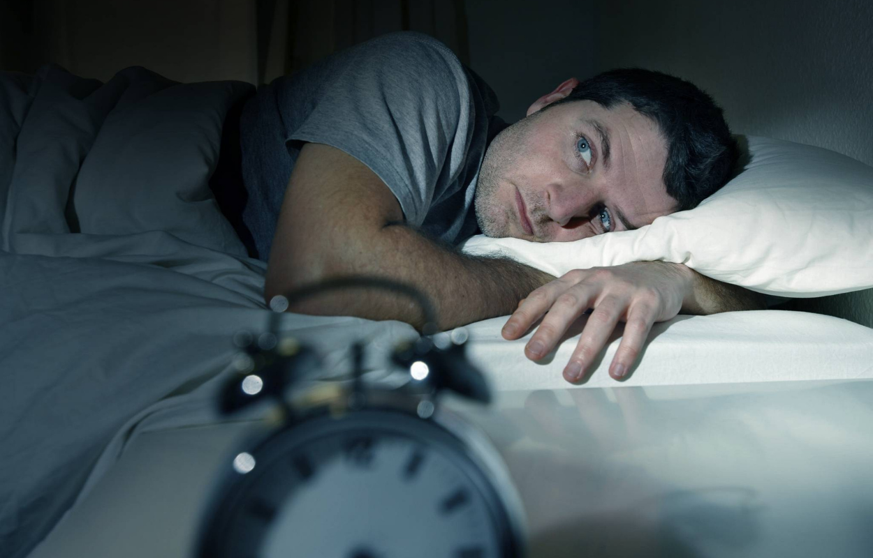 Imagem de um homem indo deitar em horário programado para dormir melhor.