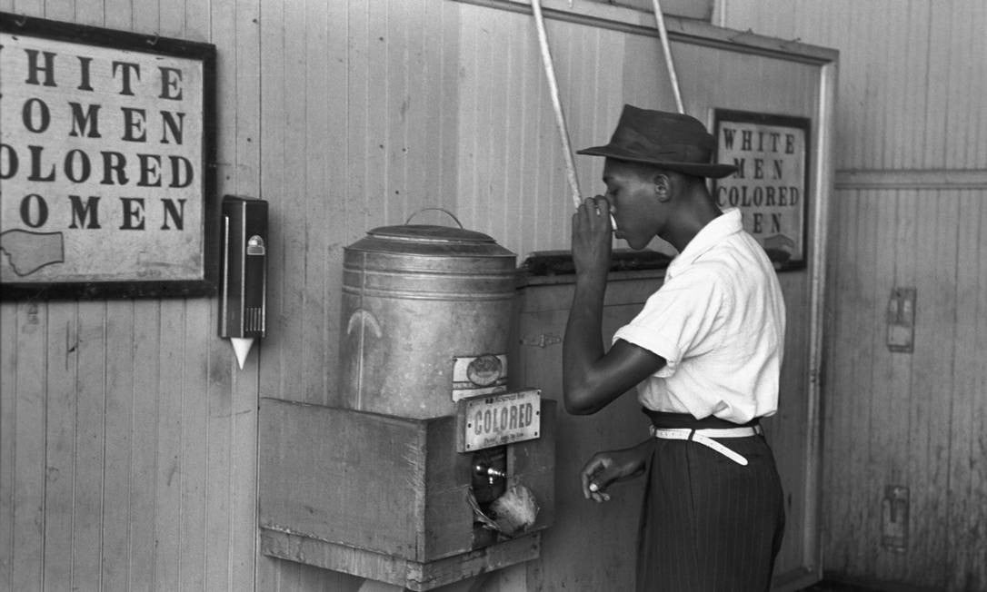 Homem a beber água no depósito próprio para os homens negros (Colored Men). 