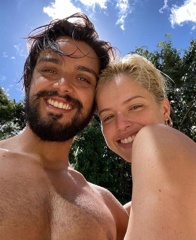 Rodrigo Simas e Agatha Moreira com rostinhos colados, de roupa de praia, com um dia lindo atrás