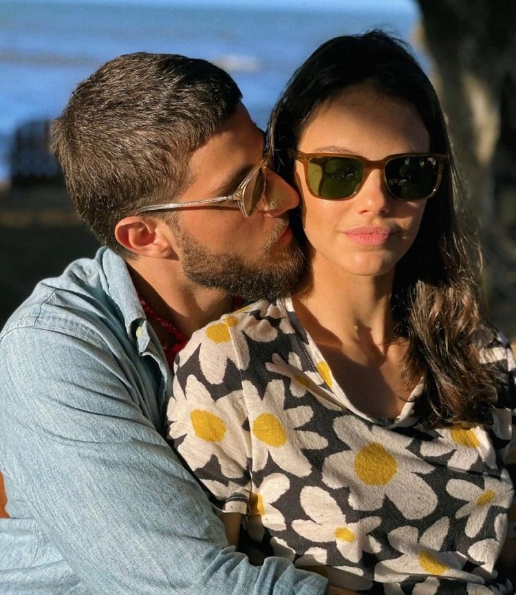 Ambos de óculos escuros, Chay Suede dá um beijo no rosto de Laura Neiva