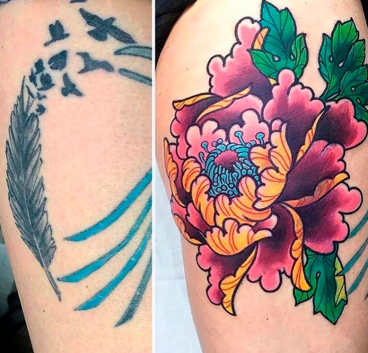 Tatuagem de uma pena azul e pássaros. Ela foi coberta por outra tatuagem, maior, de uma flor colorida.