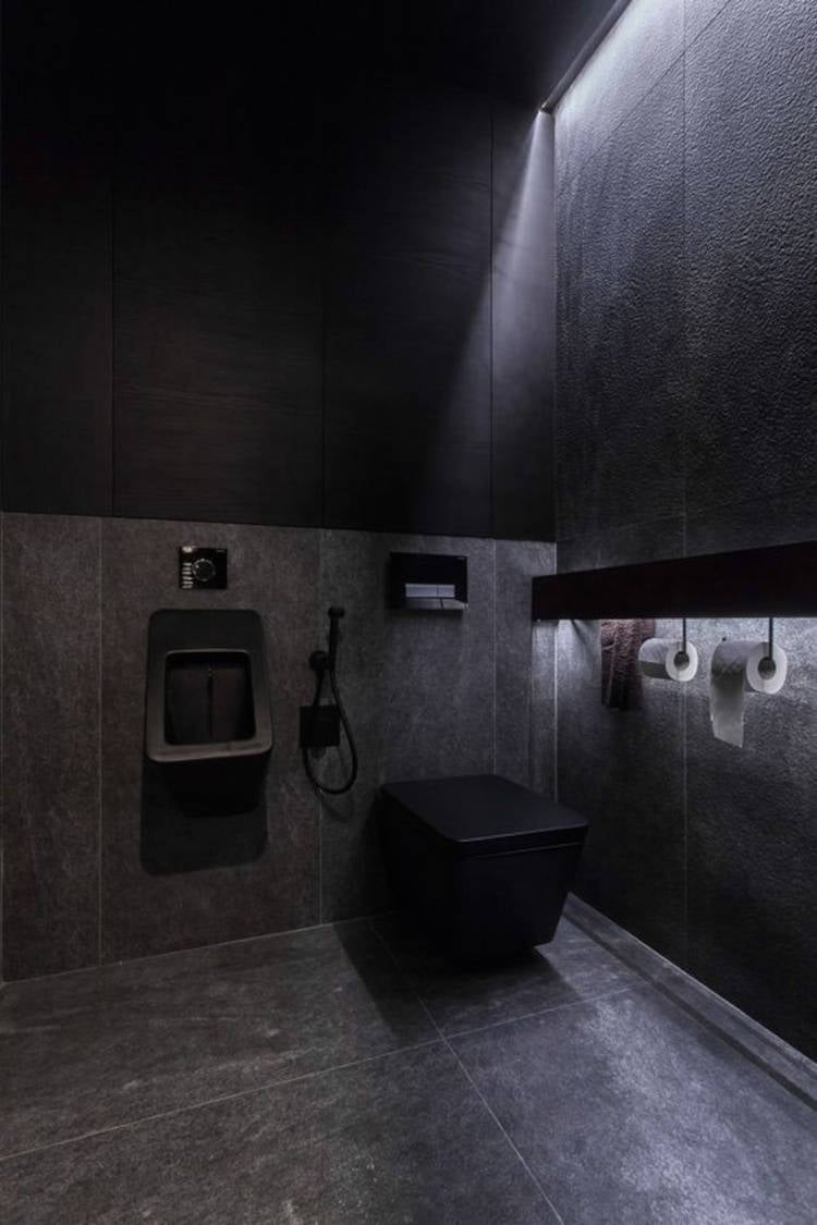 Banheiro preto com vaso e mictório.