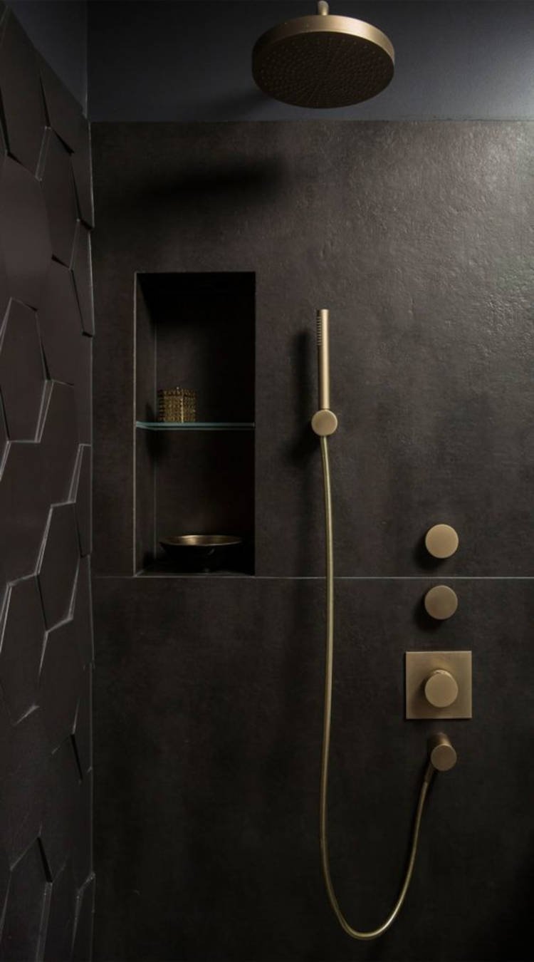 Banheiro preto com detalhes dourados.