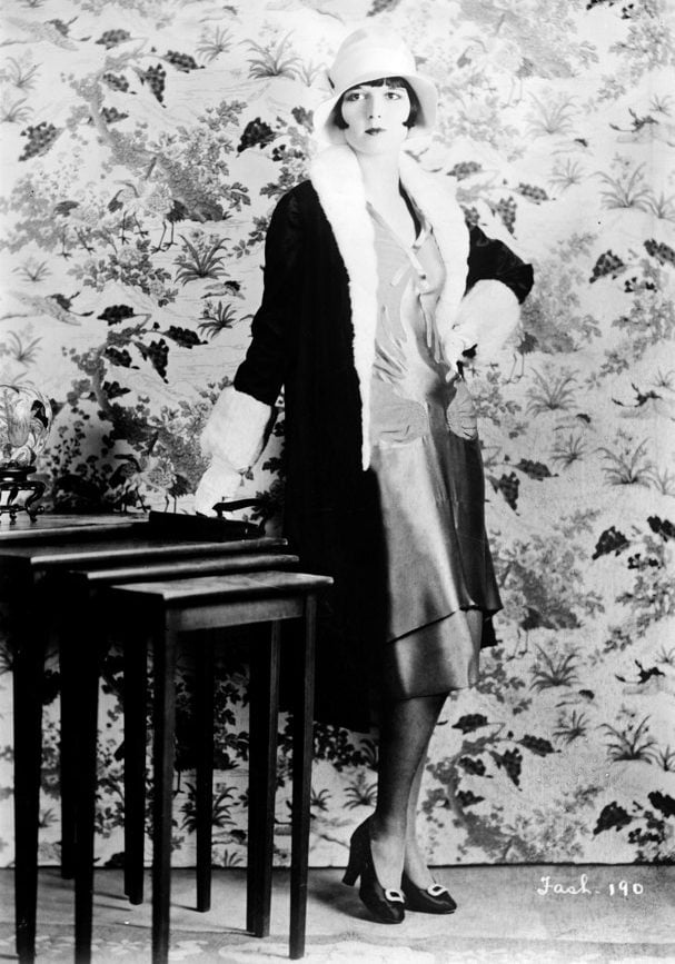 Mulher posando com vestido e chapéu dos anos 20