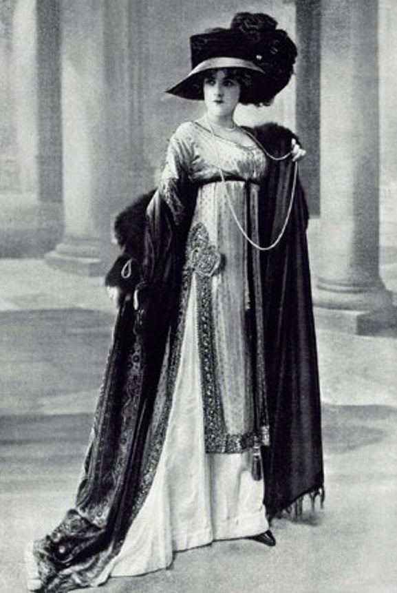 Mulher posando com vestido e chapéu com pluma. A moda dos anos 10.