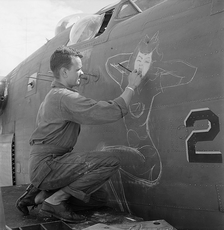 Homem pintando uma pin-up em uma aeronave, em 1944. 
