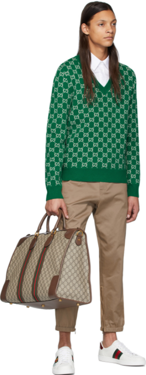 Bolsa de mão Gucci, tricô sobreposto à camisa branca e calça bege e tênis Gucci
