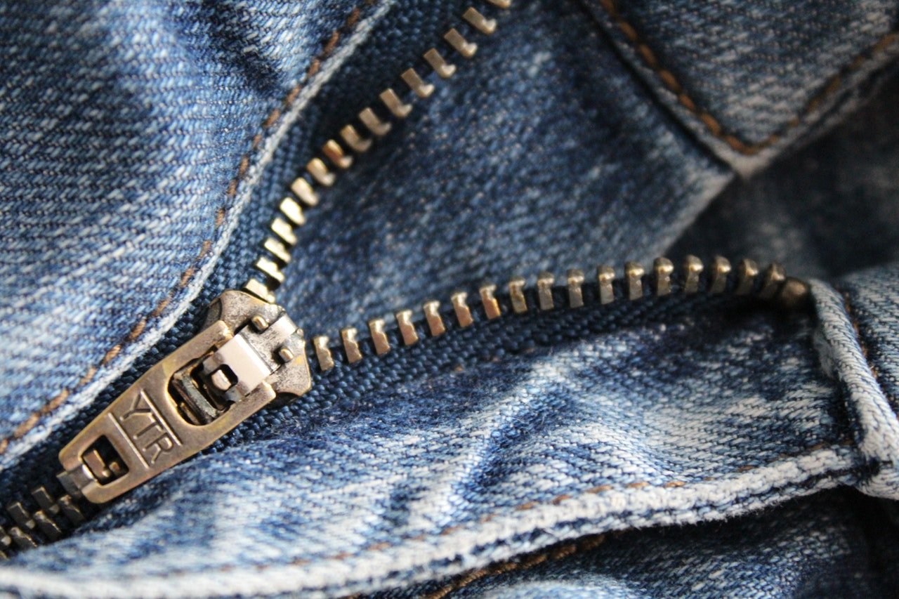 Foto do detalhe de um zíper de uma calça jeans