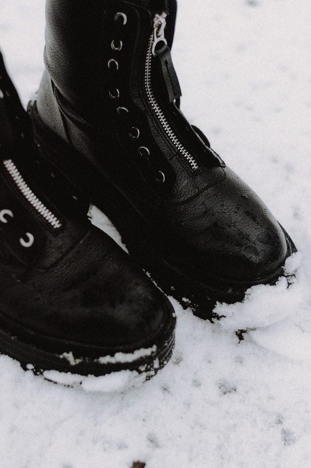 Foto de botas pretas de couro com zíper metálico na neve 