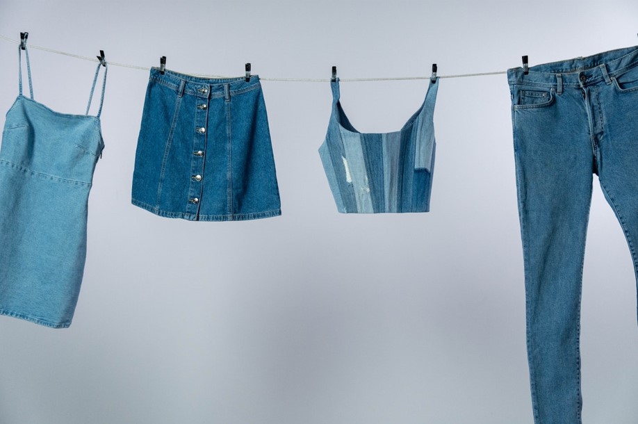 Foto de diferentes roupas jeans estendidas em um varal com fundo branco