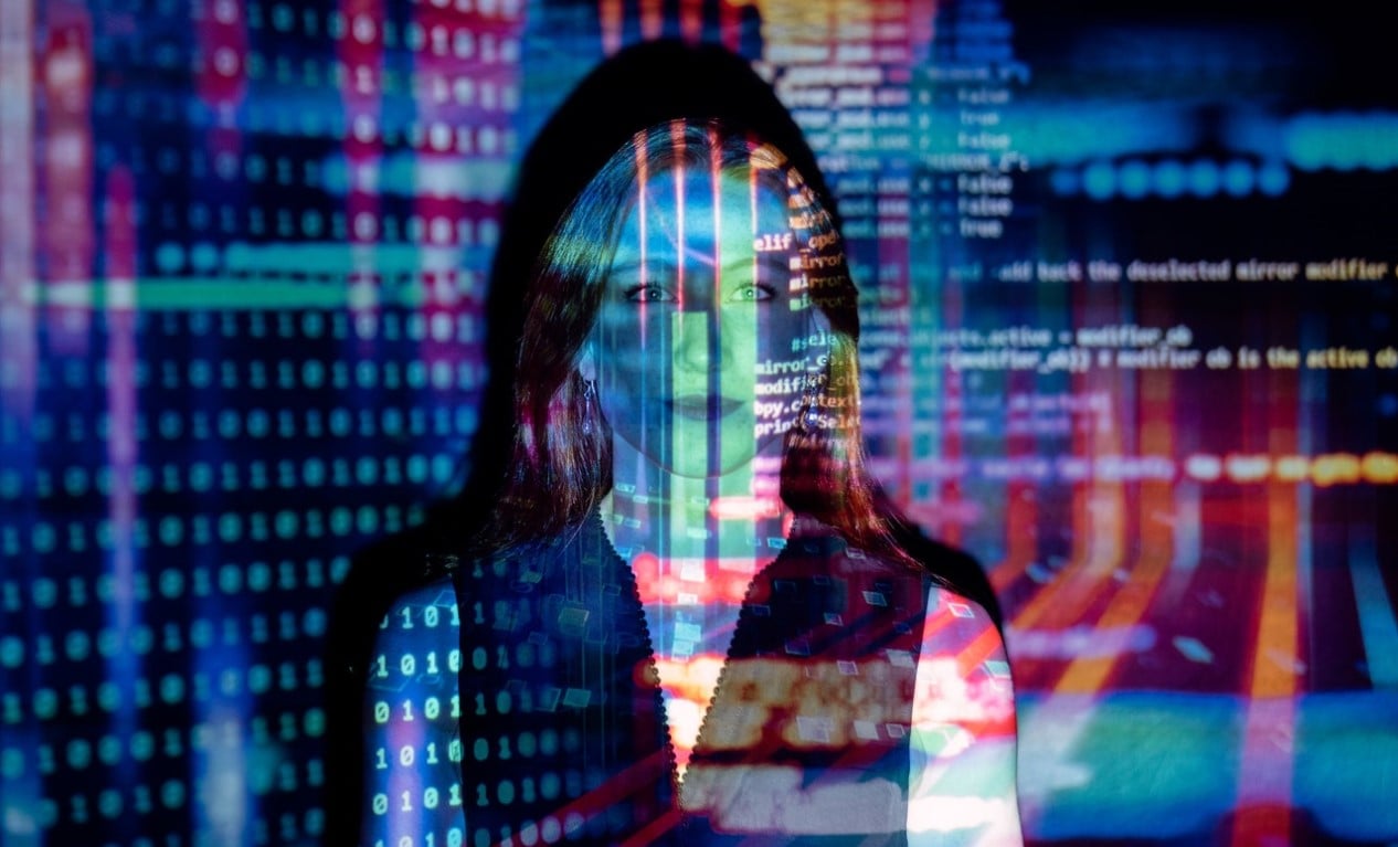 Foto de uma mulher com projeção de códigos informáticos.