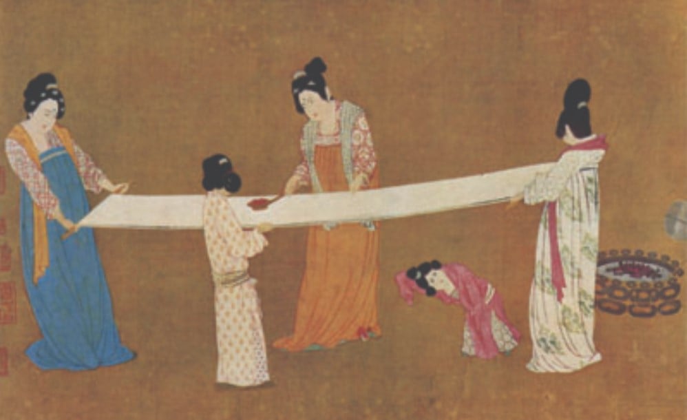Mulheres esticando os fios de seda. 