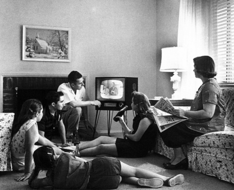 Foto em preto e branco de uma família vendo televisão em 1958. 
