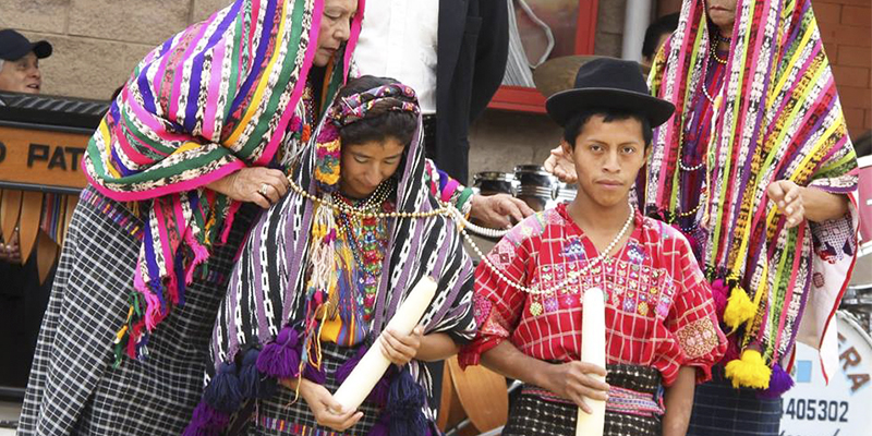 Foto de um cerimônia de casamento tradicional da Guatemala com um casal ao centro. 