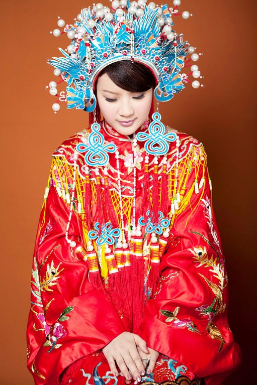 Foto de uma mulher com um vestido de noiva tradicional chinês vermelho e coroa ornamentada azul. 
