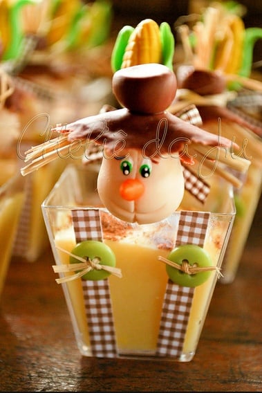 A imagem representa decorações de festa junina: doce no potinho decorado com biscuit de fantoche
