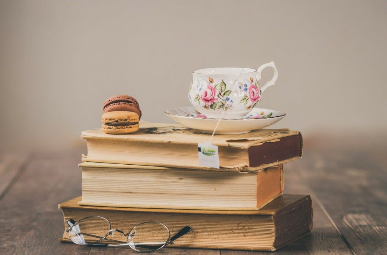 livros e um docinho e um óculos e uma xícara de chá