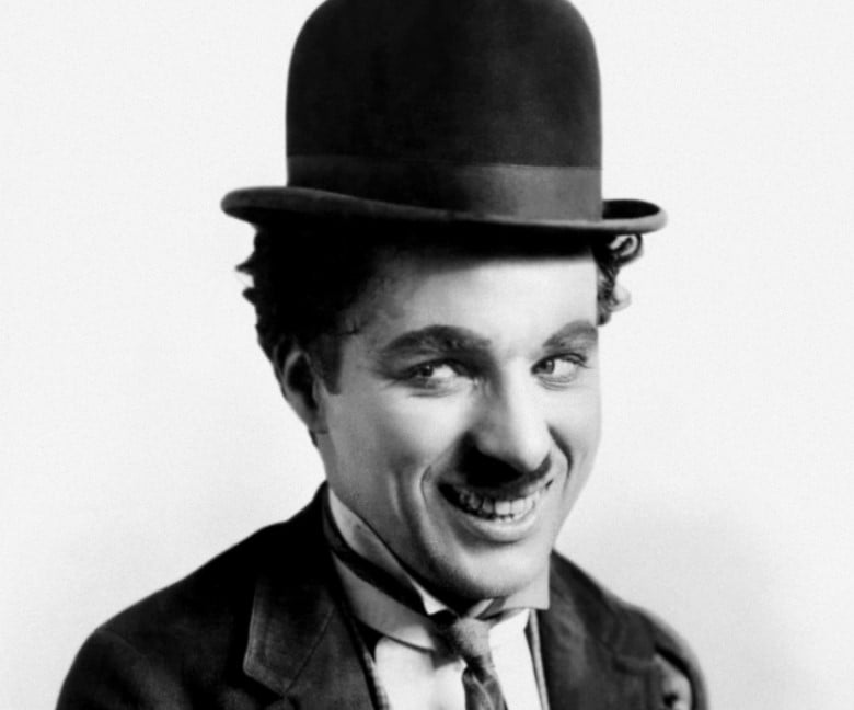 Charles Chaplin como Carlitos com bigode e chapéu coco