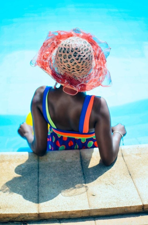 Mulher posando de costas com chapéu em uma piscina 