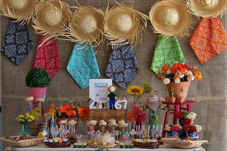 decoração de festa com painel de chapéus de palha e lenços