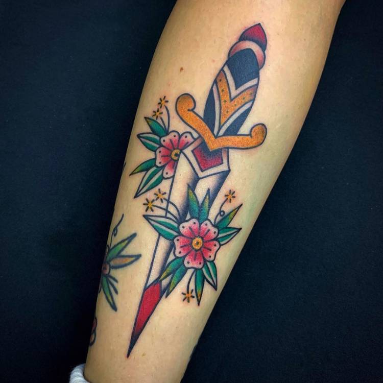 Adaga colorida old school com flores tatuada em pessoa de pele clara