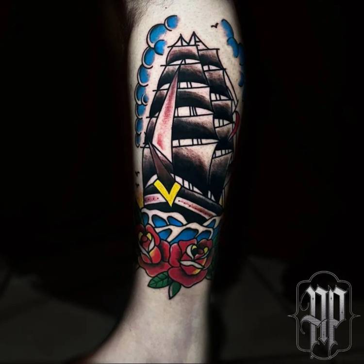 Pessoa de pele clara tatuada com barco old school em preto, amarelo, azul e vermelho