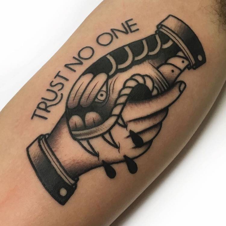 Pessoa de pele clara com tatuagem de cobra mordendo mão escrito "trust no one"