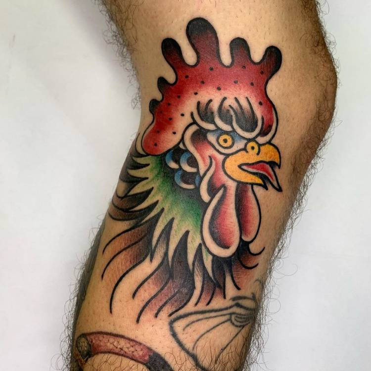 Tatuagem de galo colorido old school na perna de pessoa de pele clara