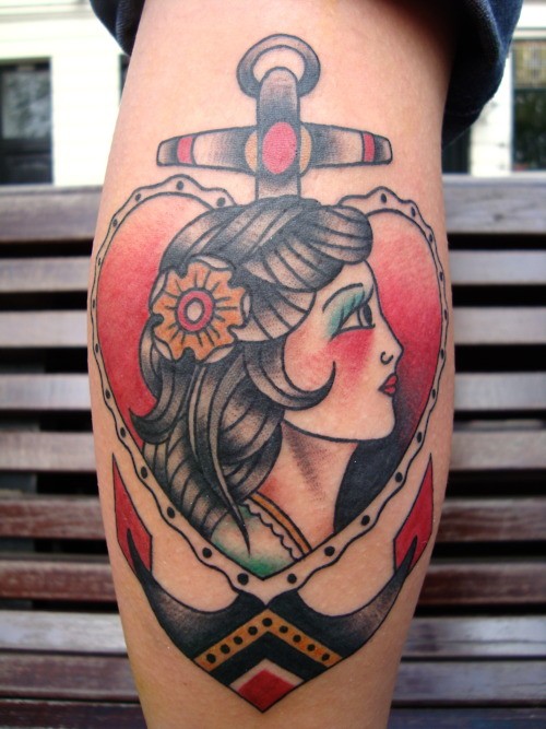 Tatuagem de mulher dentro de um coração em uma âncora em estilo Old School nas cores vermelho, preto e amarelo