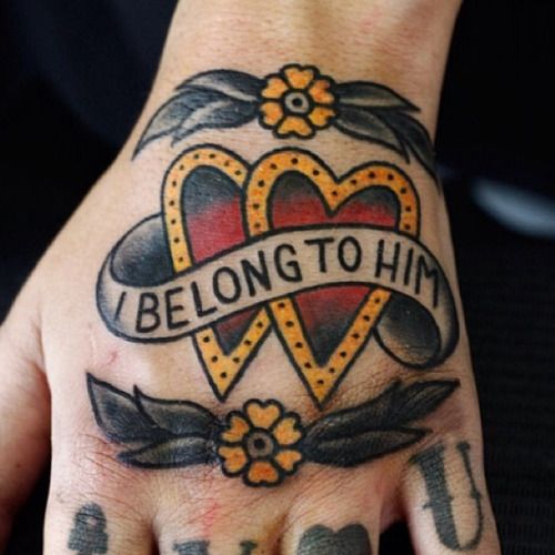 Tatuagem de dois corações vermelhos com borda amarela, flâmula escrito "I belong to him" e flores amarelas em cima e embaixo