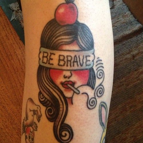 Tatuagem Old School de mulher fumando com faixa escrita "be brave" e maçã