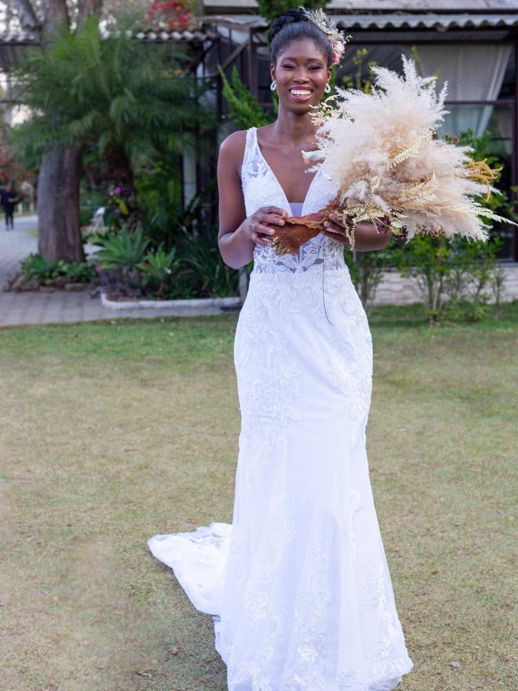 Mulher de pele negra usando vestido de noiva branco com alça e bordado com brilho