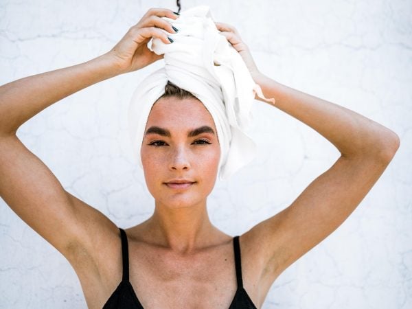 Mulher com toalha enrolada nos cabelos - Como lavar os cabelos corretamente