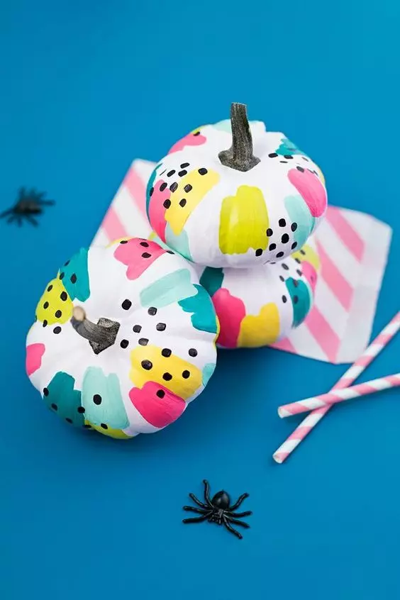Abóboras pintadas com tintas coloridas, desenhos abstratos para o Halloween - Decorada com aranhas de brinquedo. Foto de abóboras decoradas com desenhos abstratos para o Halloween.
