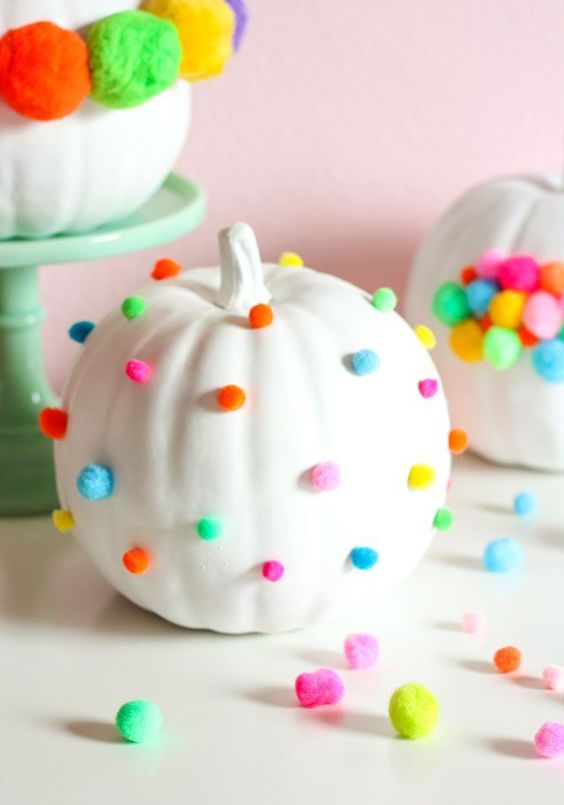 Abóboras pintadas de branco e decoradas com pompons para o Halloween. Foto de abóbora decorada com pompom para o Halloween.