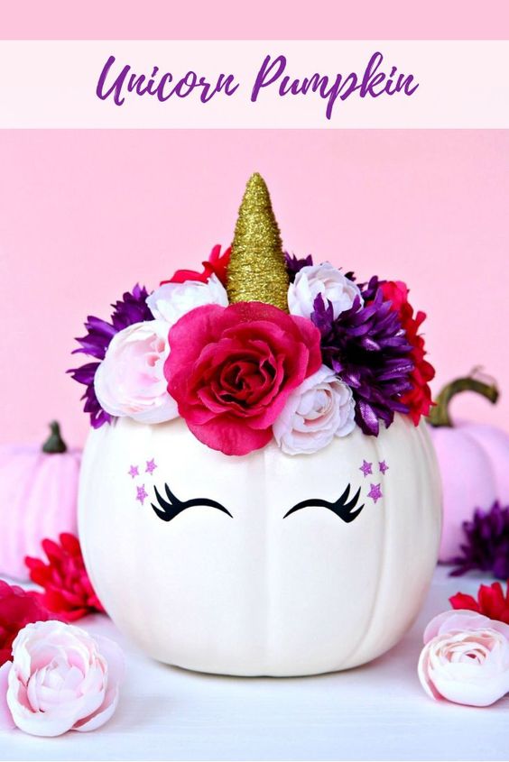 Abóbora decorada de unicórnio, com flores, chifre e olhos, para usar no Halloween. Foto de abóbora decorada de unicórnio para o Halloween.