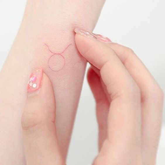 Tattoo fina de símbolo de signo vermelho no pulso de braço