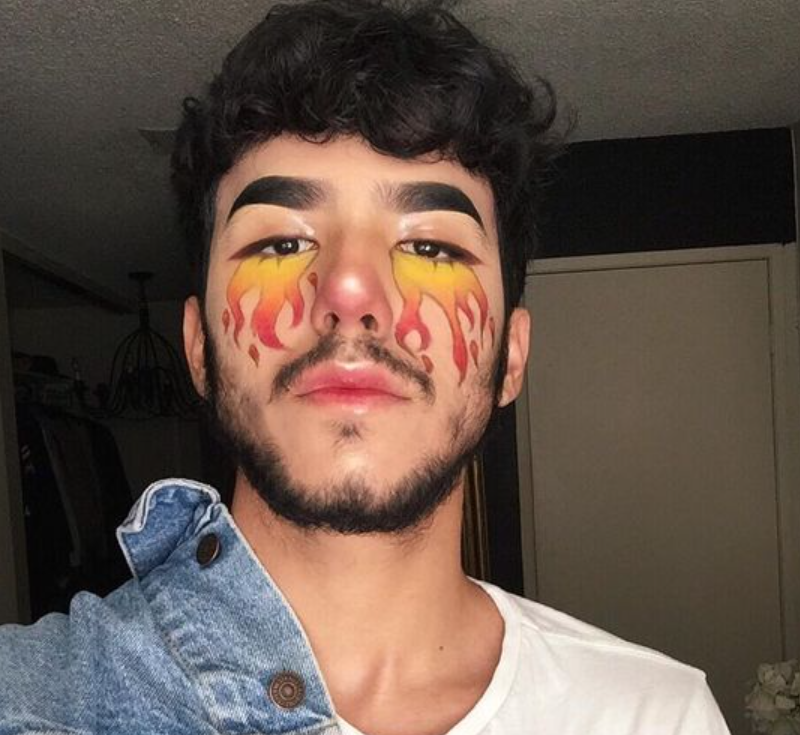 Maquiagem masculina com desenho de fogo neon no olho 