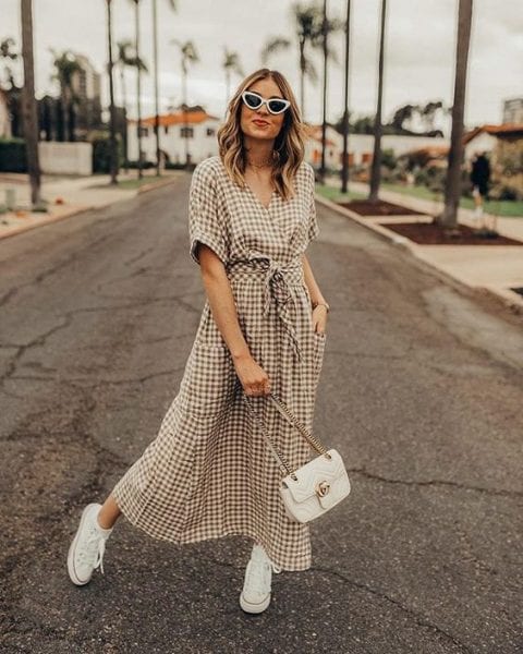 Mulher loira de pele clara usando vestido midi xadrez de marrom e branco