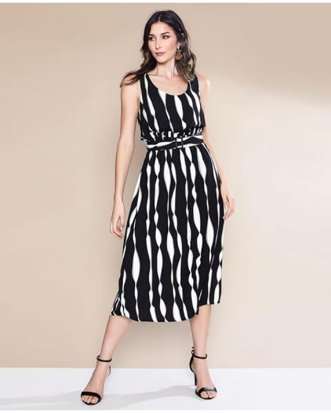 Mulher de pele clara e cabelo escuro usando vestido midi branco e preto com salto