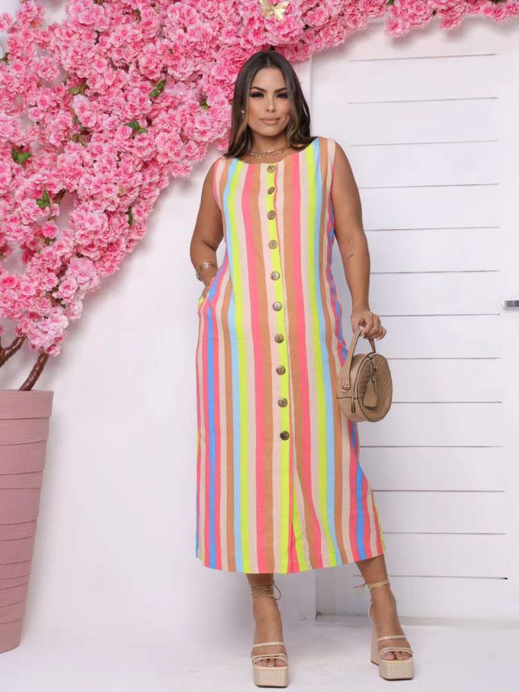 Mulher de pele morena usando vestido midi colorido em tons de laranja, roxo e amarelo com sandália