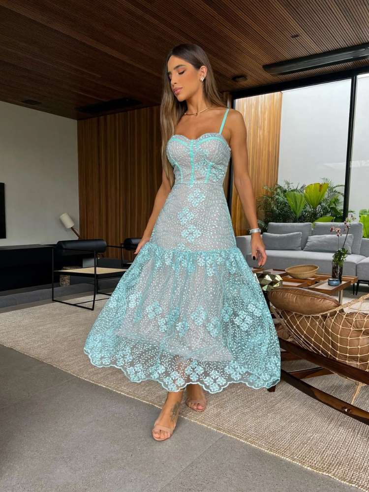 Mulher de pele clara usando vestido midi azul claro de tule bordado e salto nude claro