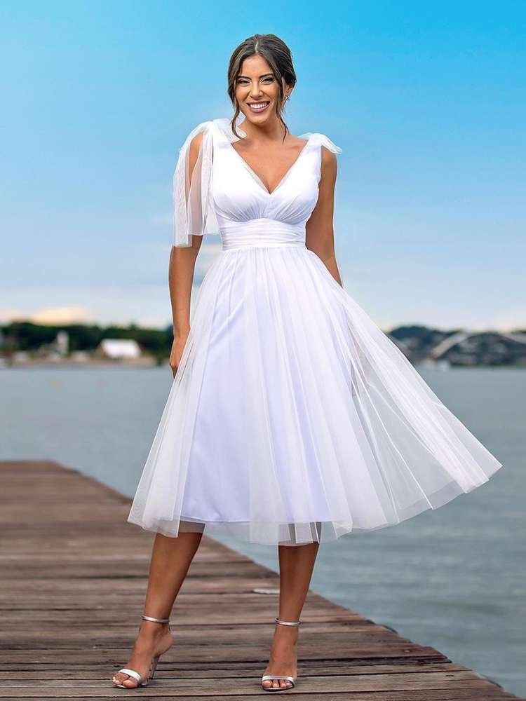 Mulher de pele clara usando vestido midi fluido branco em pier