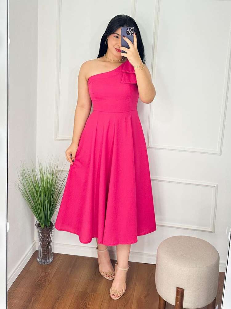 Mulher de pele clara e cabelo escuro usando estido midi rosa com laço no ombro