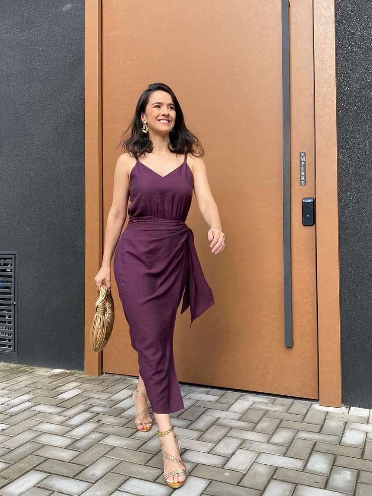 Mulher de pele clara com vestido midi envelope roxo e salto