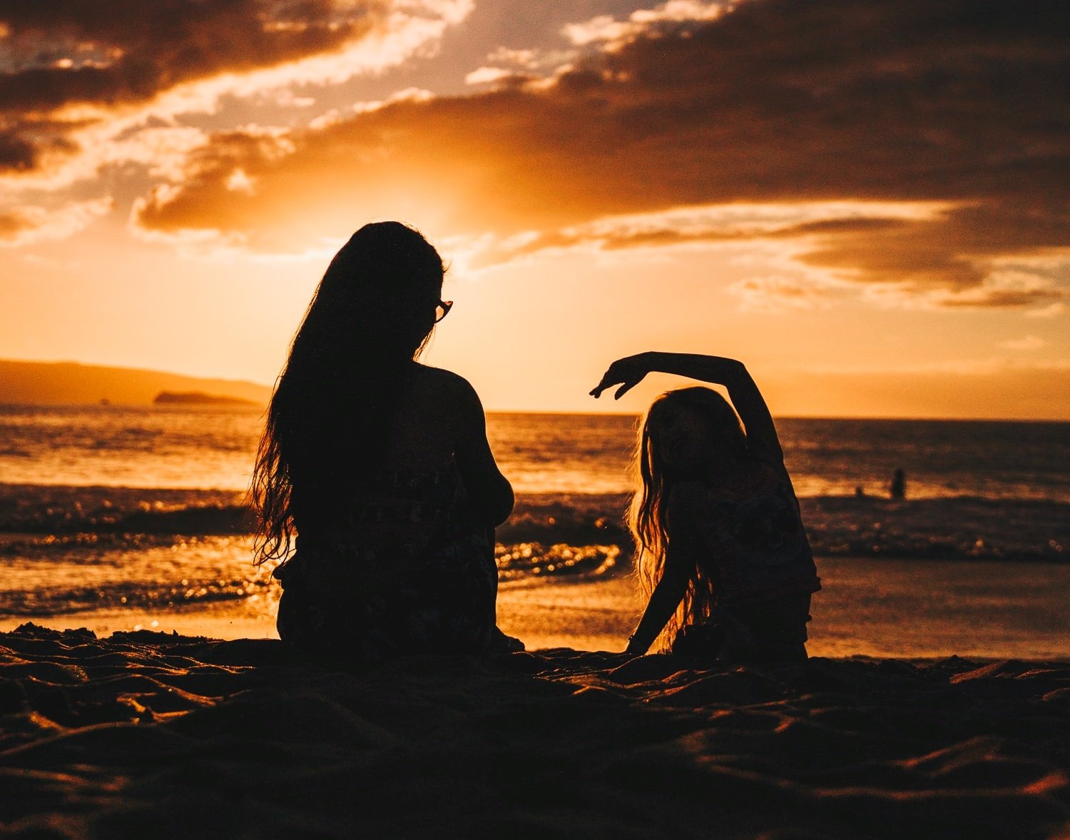 Foto de mãe e filha no pôr do sol na praia