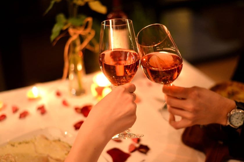 Mãos segurando taças em um jantar romântico