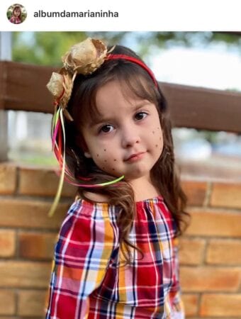 Foto de garotinha com maquiagem de festa Junina com sardas e tiara decorada com fitas e chapéu de palha Foto de garotinha com maquiagem de festa Junina com sardas e tiara decorada com fitas e chapéu de palha