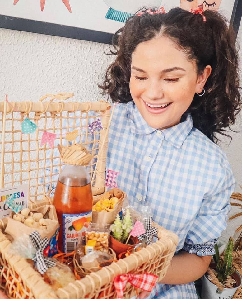 Menina com traje junino segura cesta de festa Junina delivery - Com várias cominhas tradicionais de São João Menina com traje junino segura cesta de festa Junina delivery - Com várias cominhas tradicionais de São João